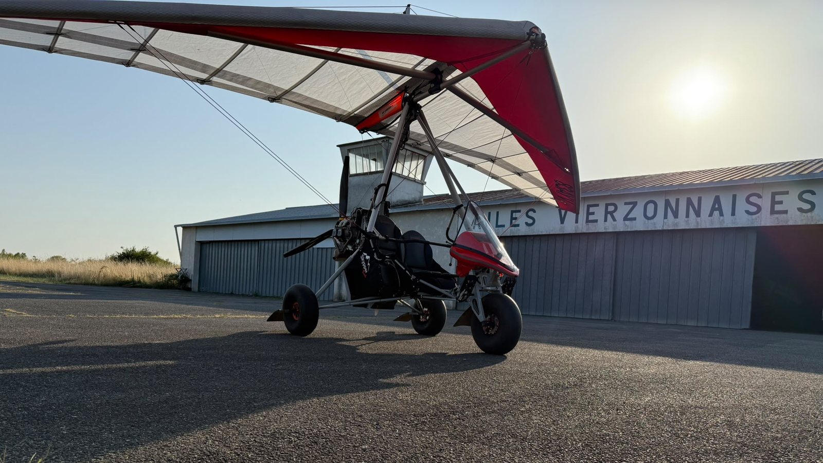 Le pendulaire Skypper Bush F-JJXS, aile blanche et rouge, devant le hangar des Ailes Vierzonnaises